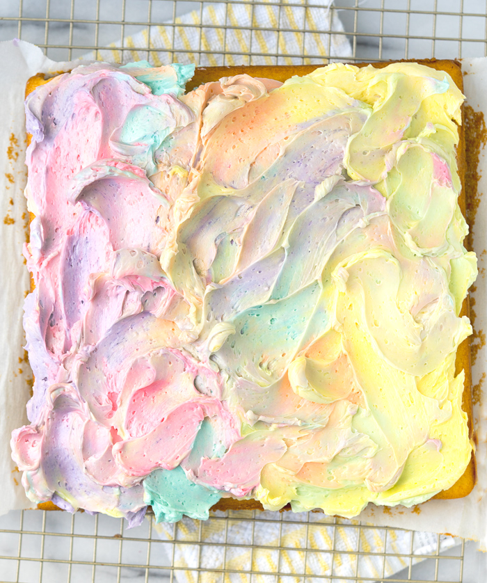 Rainbow Frosted Sheet Cake. I'm in love with this simple, moist yellow cake enrobed in a blanket of rainbow swirled swiss meringue buttercream. | thesugarcoatedcottage.com