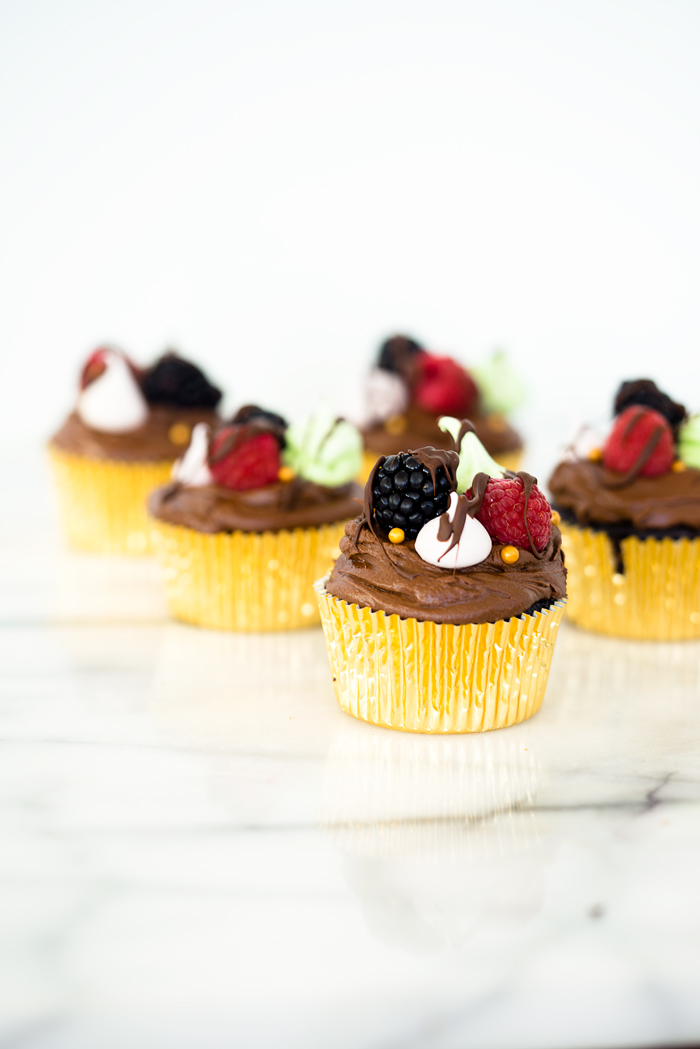 Chocolatey Fudge Cupcake Recipe. Moist, fluffy, pillowy cupcakes in a swirl of fudge chocolate frosting. Decorated in fresh berries and crisp meringues. | thesugarcoatedcottage.com