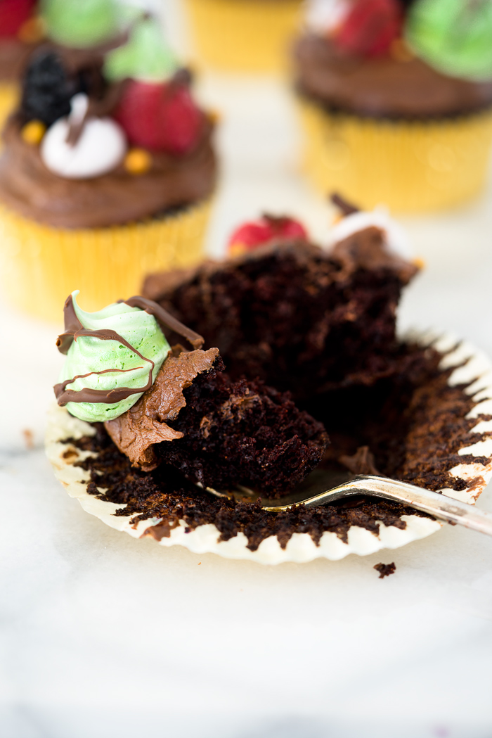 Chocolatey Fudge Cupcake Recipe. Moist, fluffy, pillowy cupcakes in a swirl of fudge chocolate frosting. Decorated in fresh berries and crisp meringues. | thesugarcoatedcottage.com