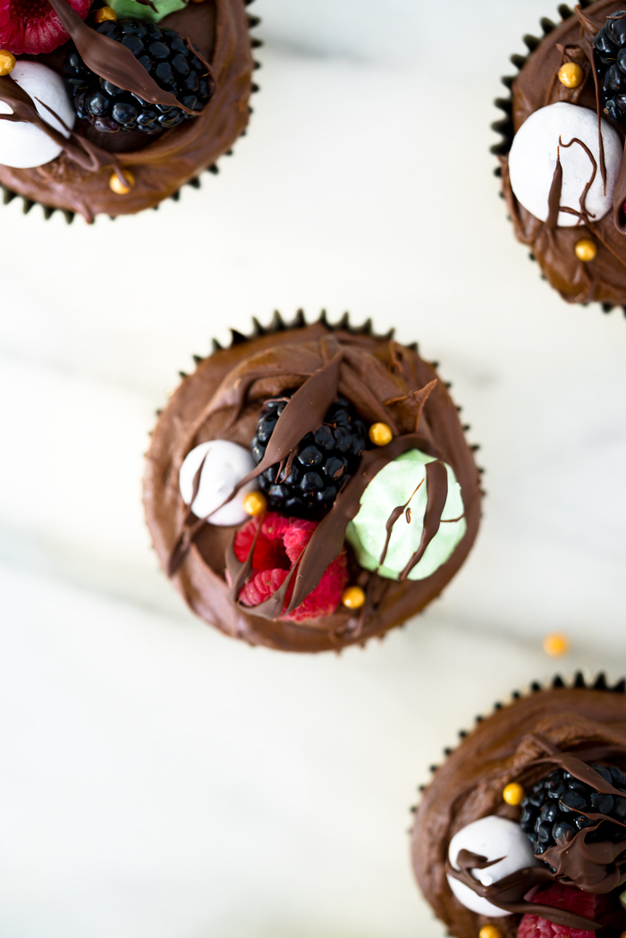 Chocolatey Fudge Cupcake Recipe. Moist, fluffy, pillowy cupcakes in a swirl of fudge chocolate frosting. Decorated in fresh berries and crisp meringues. | thesugarcoatedcottage.com