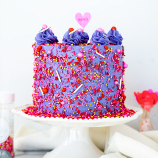 Valentines Red Velvet Cake Recipe. Three layers of southern red velvet cake enrobed in purple swiss meringue buttercream and valentines inspired sprinkles. | thesugarcoatedcottage.com