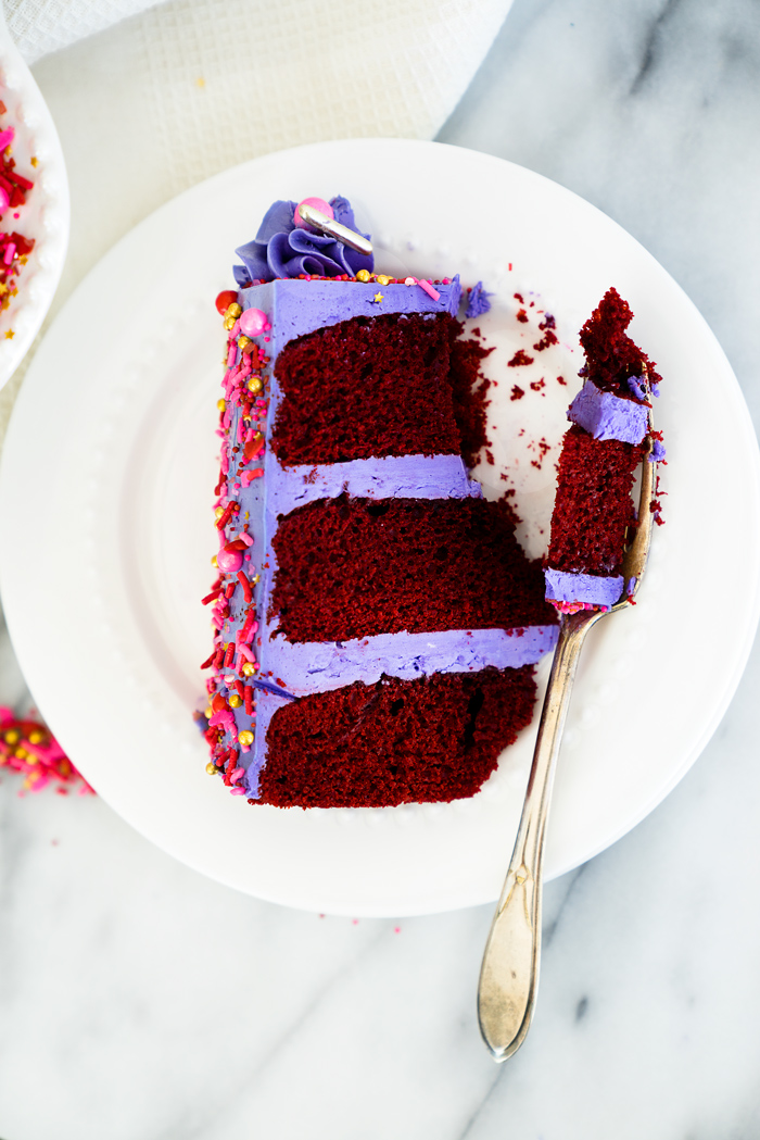 Valentines Red Velvet Cake Recipe. Three layers of southern red velvet cake enrobed in purple swiss meringue buttercream and valentines inspired sprinkles. | thesugarcoatedcottage.com