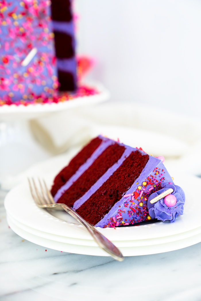 Valentines Red Velvet Cake Recipe. Three layers of southern red velvet cake enrobed in purple swiss meringue buttercream and valentines inspired sprinkles. | thesugarcoatedcottage.com