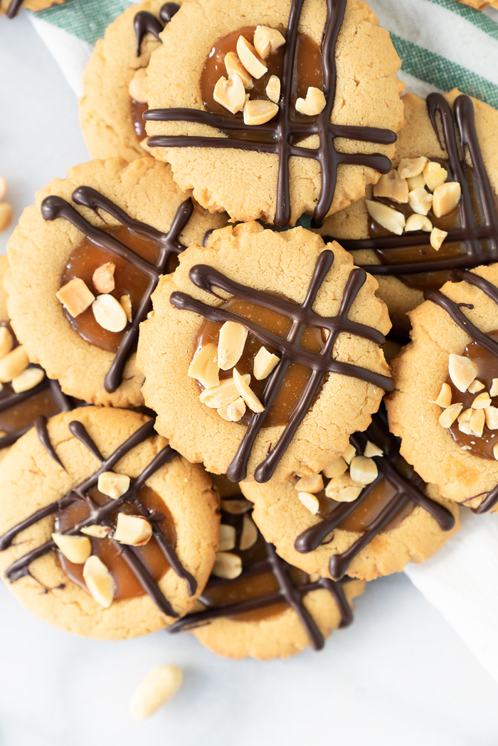 Caramel Peanut Butter Cookies. Crispy edged soft peanut butter cookies with a pool of caramel and chocolate drizzle. Cookies, peanut butter, caramel | thesugarcoatedcottage.com