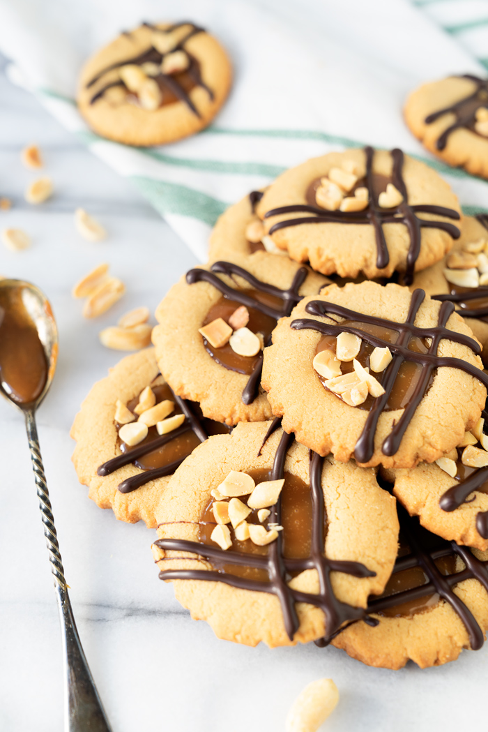 Caramel Peanut Butter Cookies. Crispy edged soft peanut butter cookies with a pool of caramel and chocolate drizzle. Cookies, peanut butter, caramel | thesugarcoatedcottage.com